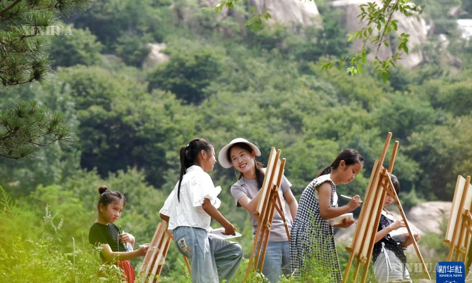 တရုတ်နိုင်ငံ ဆန်းတုန်းပြည်နယ်၊ ကျီးပေါ်မြို့၊ ရီယွမ်ခရိုင်၊ ရှီချောင်းမြို့နယ်၊ ဟေးရာကျေးရွာတွင် စေတနာ့ဝန်ထမ်း (ဝဲ၊ တတိယ) က ကလေးများအား ပန်းချီရေးဆွဲရန် သင်ကြားပေးနေသည်ကို ၂၀၂၆ ခုနှစ် ဇူလိုင် ၁၈ ရက်က တွေ့ရစဉ် (ဆင်ဟွာ)