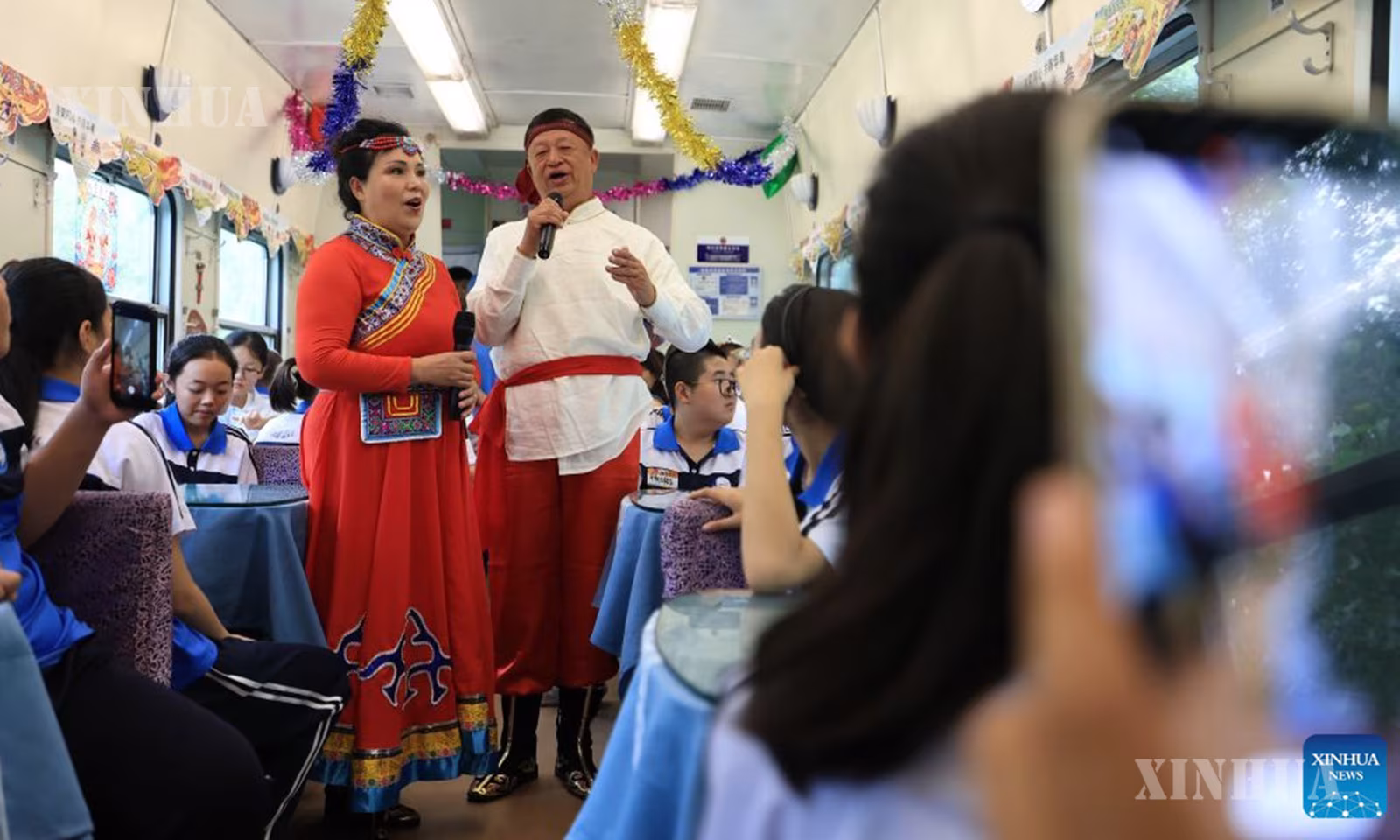 တရုတ်နိုင်ငံ အရှေ့မြောက်ပိုင်း ဟေးလုံကျန်းပြည်နယ်မှ မြို့တော်ပေကျင်းသို့ လေ့လာရေးခရီးအတွက် အထူးရထားတွင် ကျောင်းသား၊ ကျောင်းသူများအား မွန်ဂိုလီးယားသီချင်းများဖြင့် သီဆိုနေသည့် ဖျော်ဖြေတင်ဆက်သူများကို ၂၀၂၆ ခုနှစ် ဩဂုတ် ၉ ရက်က တွေ့ရစဉ် (ဆင်ဟွာ)